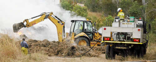 Workers try to extinguish a cane trash fire. Workers try to extinguish a cane trash fire.